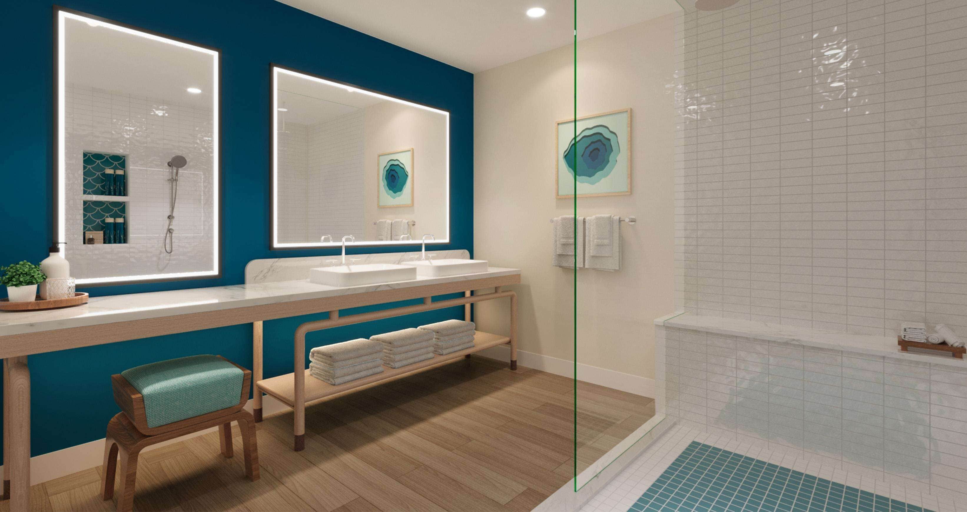 Un baño moderno con un espejo grande, dos lavamanos, una ducha y un banco.