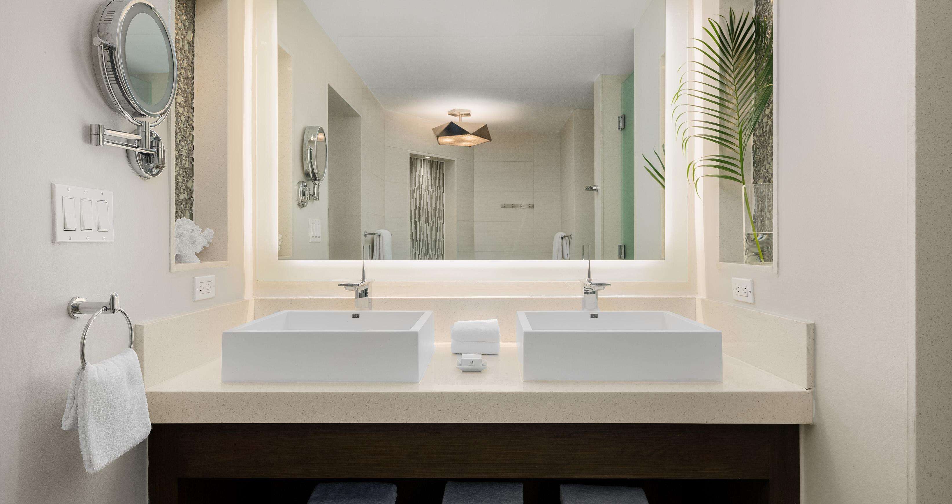 A modern bathroom with two sinks, a large mirror, and a towel rack.