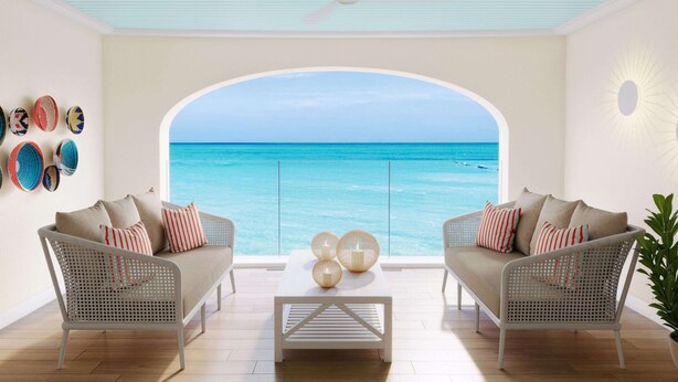 A room with two wicker sofas facing a large arched window overlooking the sea.