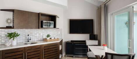 A modern kitchen with a built-in microwave, a large flat-screen TV, and a dining area with a table and chairs.