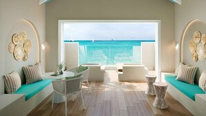 A modern room with a large window overlooking the sea, featuring a sofa, a table, and decorative wall art.