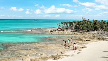 En la playa, playa de arena blanca, camastros y sombrillas