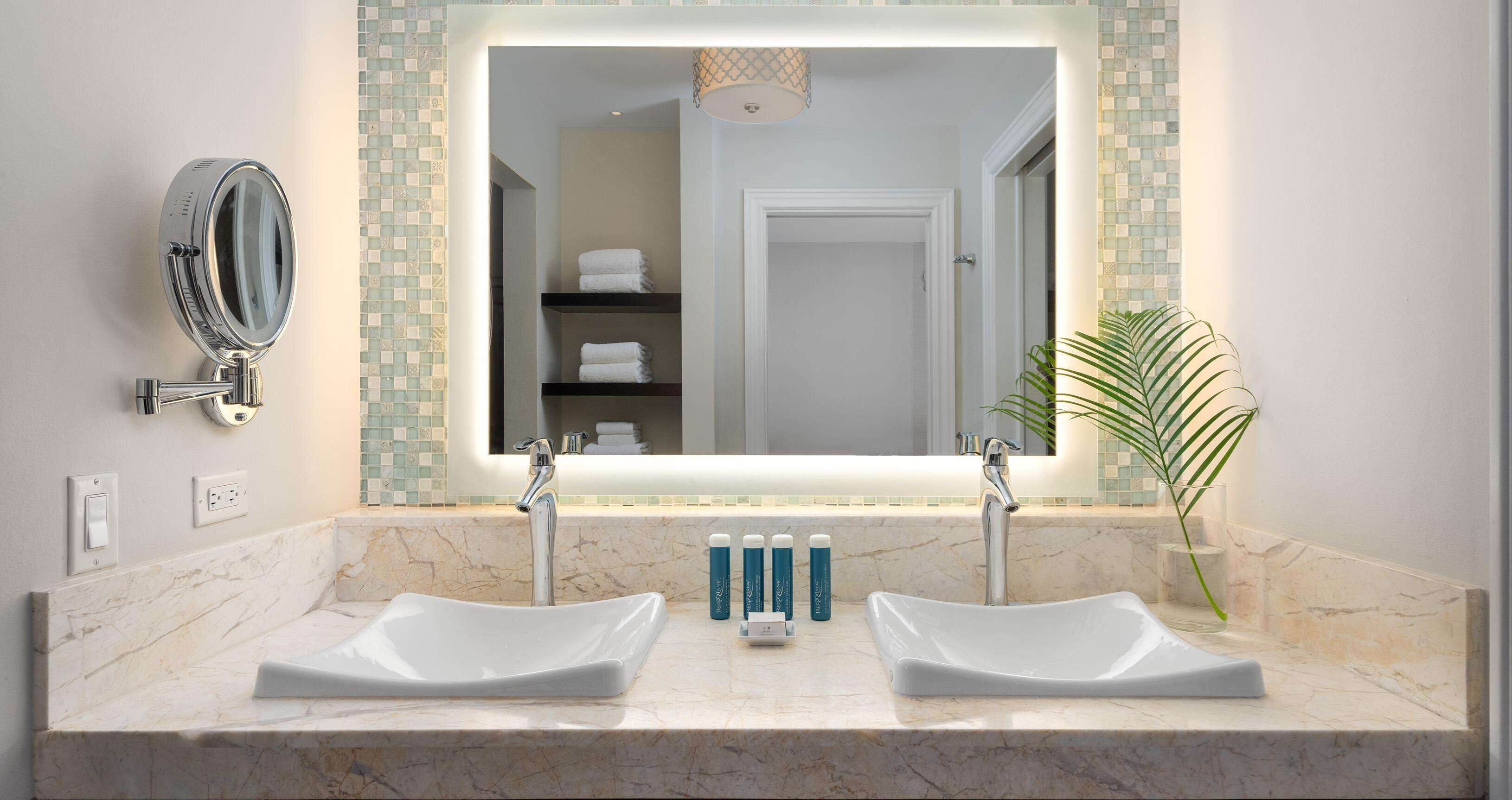 A bathroom with two sinks, a large mirror, and a towel rack.