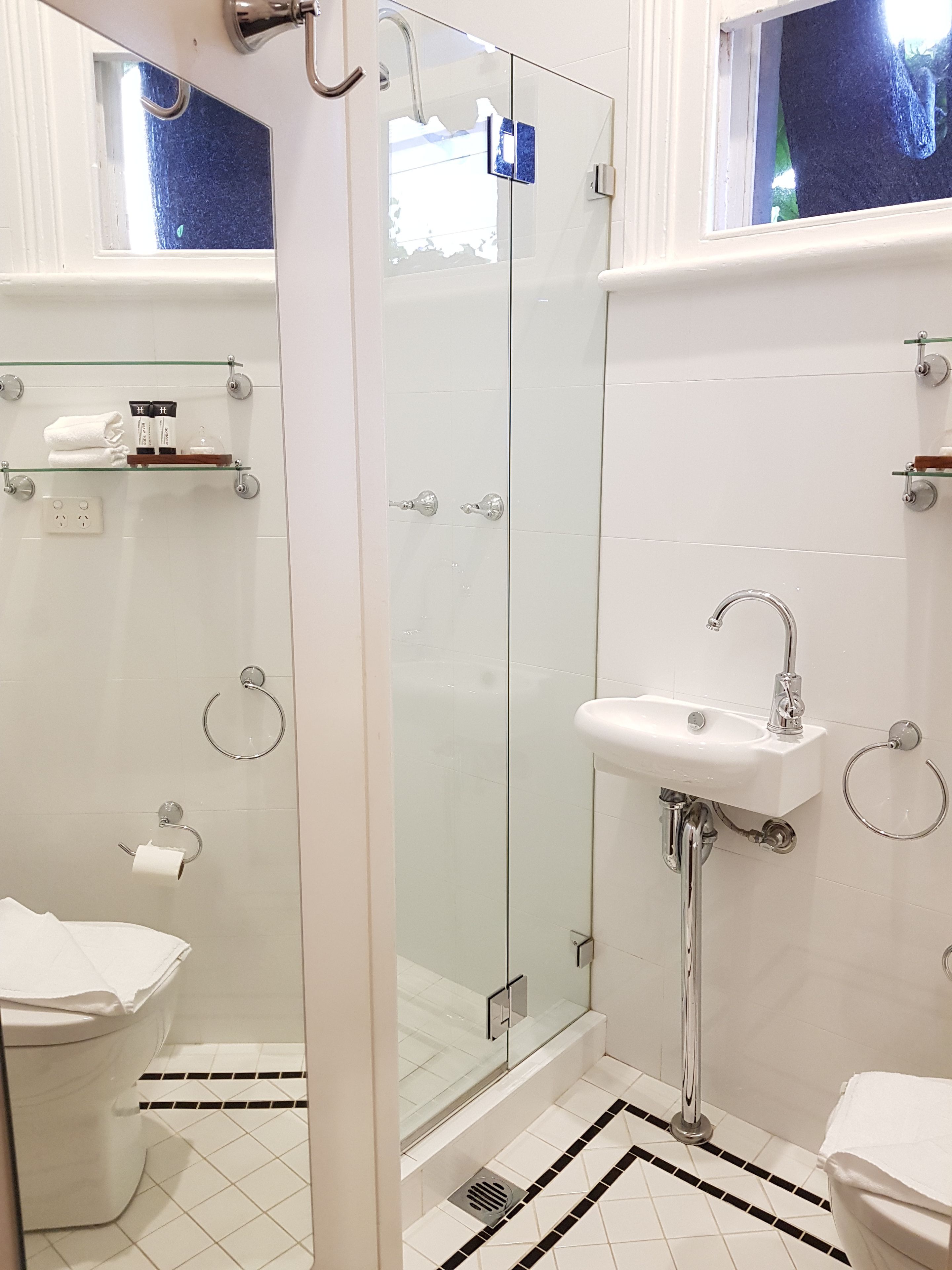 Une salle de bain moderne avec une douche à l’italienne en verre, un lavabo blanc et des toilettes.