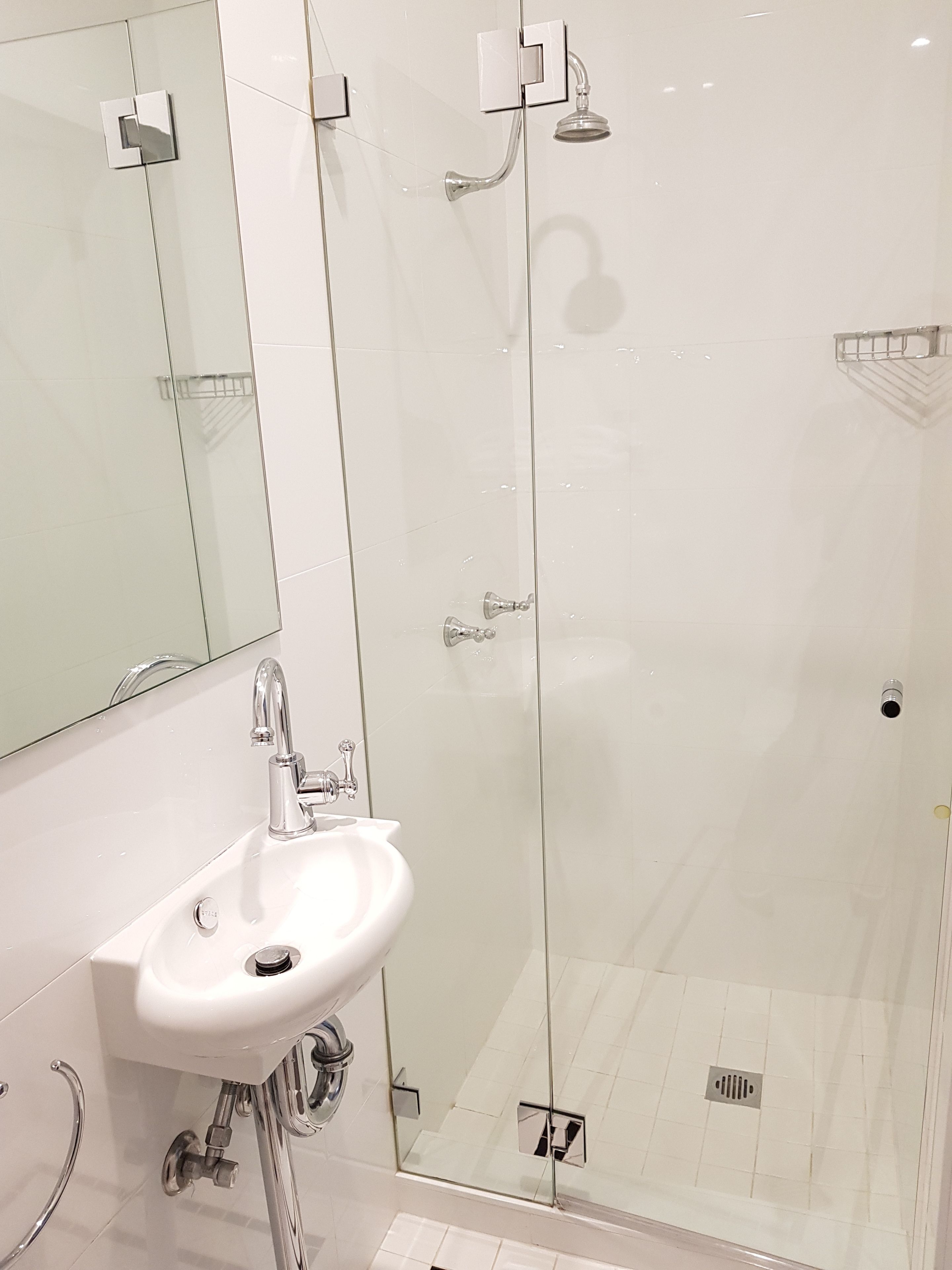 Un baño moderno con ducha de vidrio, lavabo blanco y espejo.