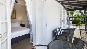 Un dormitorio con cama, mesita de noche, lámpara y ventana con cortina.
