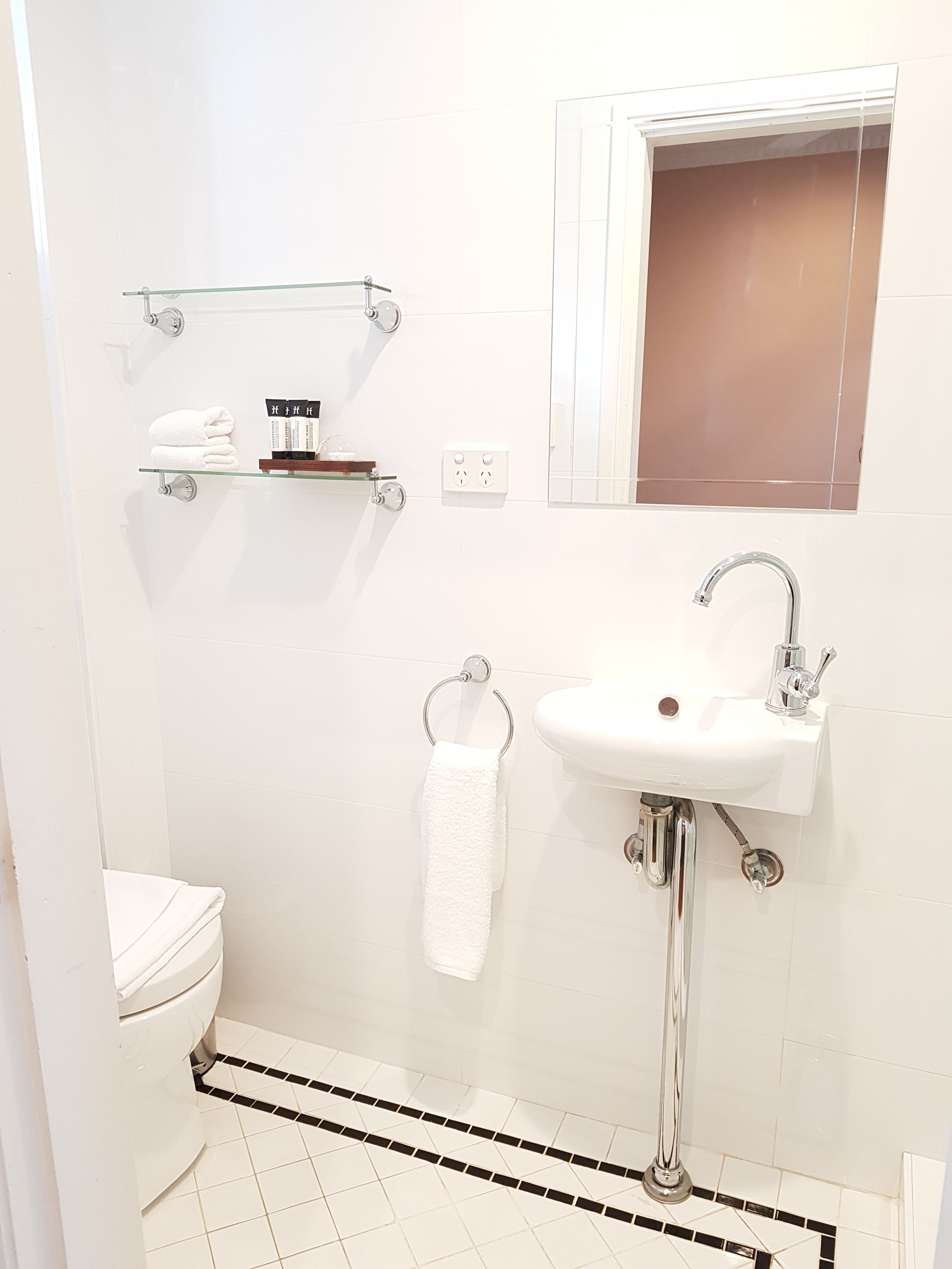 A bathroom with a white toilet, a sink with chrome fixtures, and a towel rack.