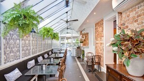 Un restaurante con una barra larga, cabinas y plantas colgantes.