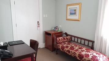 A bedroom with a bed, a desk, a chair, a wardrobe, and a framed picture on the wall.