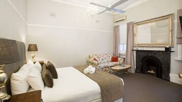 A hotel room with a bed, a sofa, a fireplace, and a large mirror.