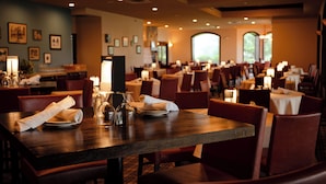 A restaurant with tables set for dining, candles, and framed pictures on the walls. - The Osthoff Resort (Elkhart Lake)