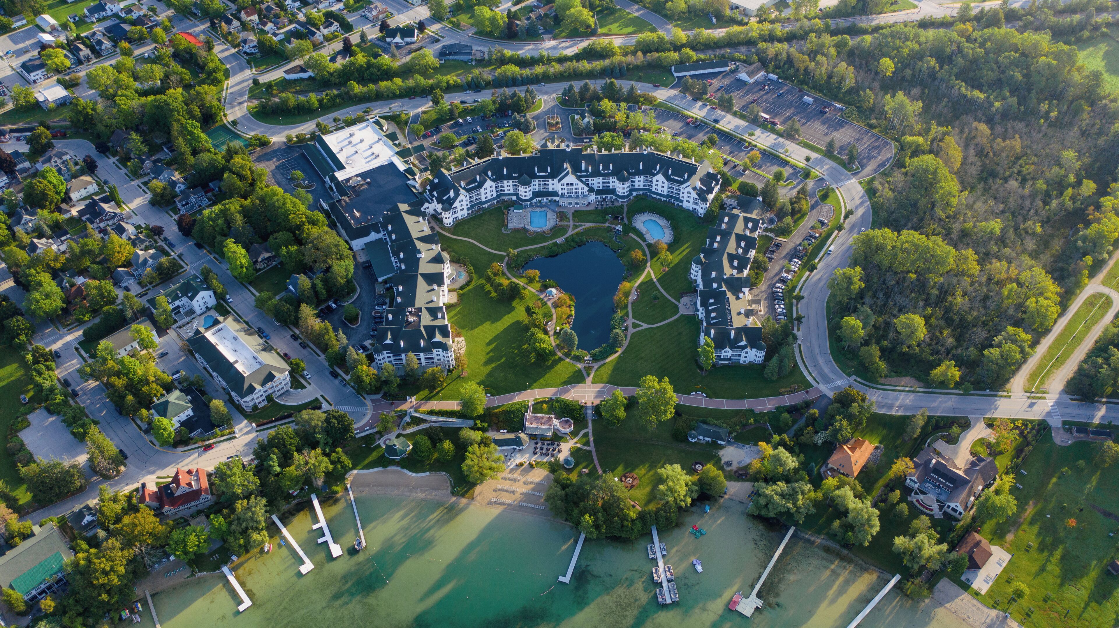 An aerial view of a residential area with a large central building, a lake, and surrounding greenery.