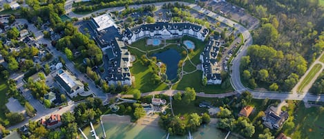 An aerial view of a residential area with a large central building, a lake, and surrounding greenery.