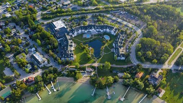 Vista aérea de una zona residencial con un edificio grande en el centro, un lago y vegetación circundante.