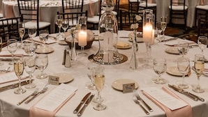 A banquet hall with round tables, candles, and a central floral arrangement. - The Osthoff Resort (Elkhart Lake)