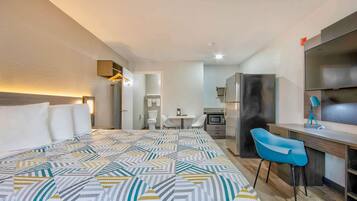 Une chambre d’hôtel avec un grand lit, un bureau avec une chaise, un four à micro-ondes et une télévision.