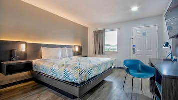 Una habitación de hotel moderna con una cama grande, mesitas de noche, un escritorio con silla, un televisor y una ventana con cortinas.
