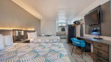 A modern hotel room with a large bed, a desk, a chair, a TV, and a wardrobe.