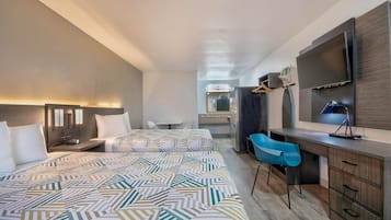 A hotel room with a large bed, a desk with a chair, a mirror, and a TV.