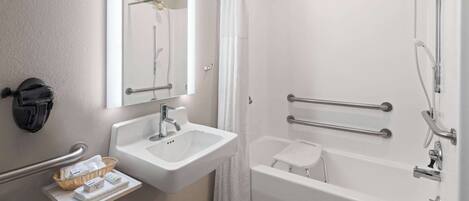 A modern bathroom with a sink, mirror, shower, and grab bars.