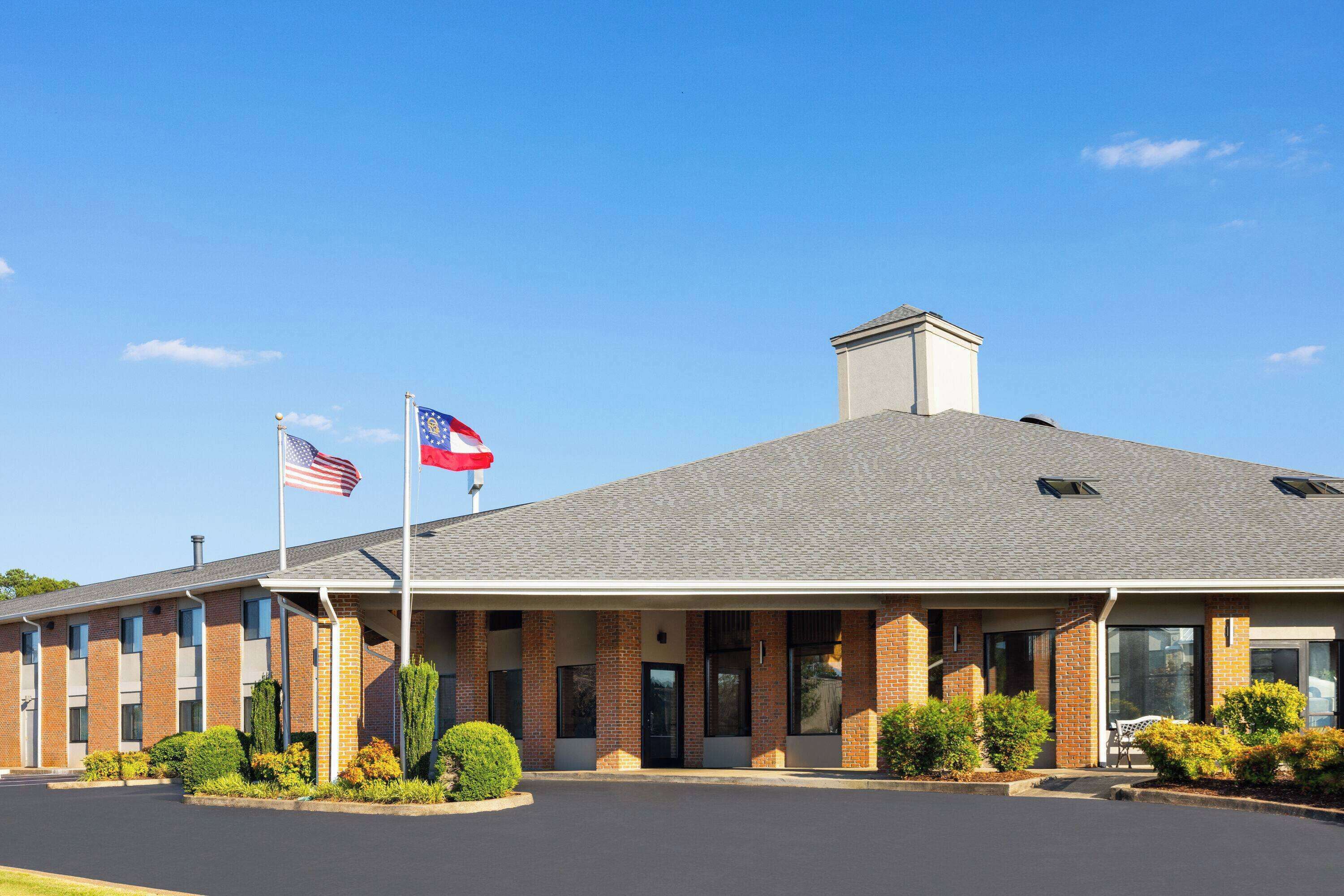 A two-story building with a brick facade, a flat roof, and a covered entrance area.