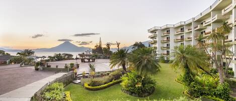 A hotel with a landscaped garden, a pool, and a view of a mountain.