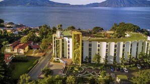 A hotel with a central courtyard, surrounded by lush greenery and a view of a lake with mountains in the background. - Porta Hotel del Lago (Panajachel)