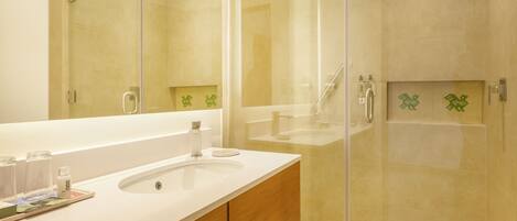 A modern bathroom with a glass-enclosed shower, a large mirror, and a wooden vanity.