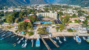 An aerial view of a coastal town with a marina, buildings, and mountains in the background. - Porta Hotel del Lago (Panajachel)
