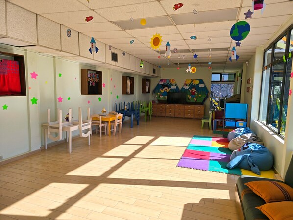 A classroom with educational decorations, wooden furniture, and a large window. - Porta Hotel del Lago (Panajachel)