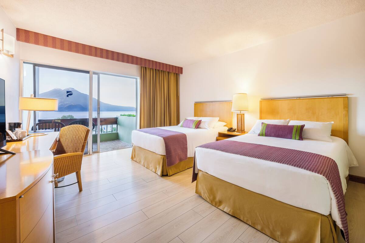 A hotel room with two beds, a desk, and a chair.