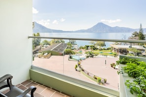 A balcony with a view of a swimming pool, outdoor seating, and a mountainous landscape. - Porta Hotel del Lago (Panajachel)