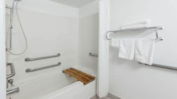 Ein Badezimmer mit Bodendusche, Haltegriffen, einer Holzablage und einem Handtuchhalter.