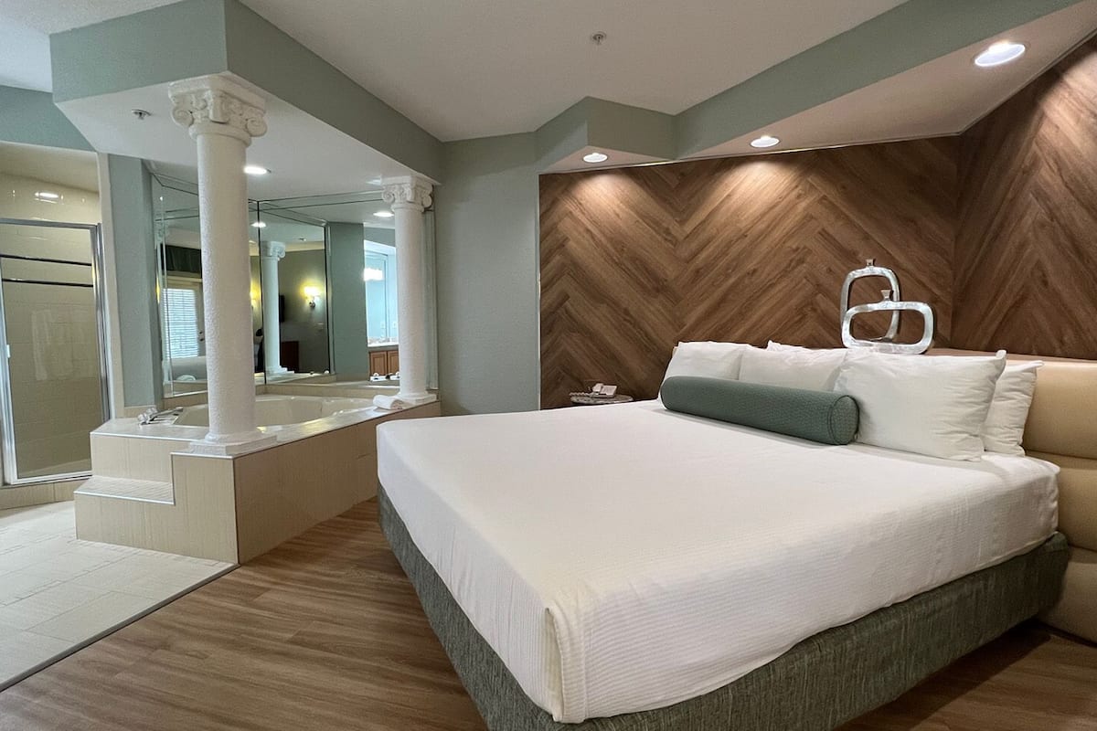 Un dormitorio moderno con una cama grande, un tocador empotrado y una pared con estampado de espiga.