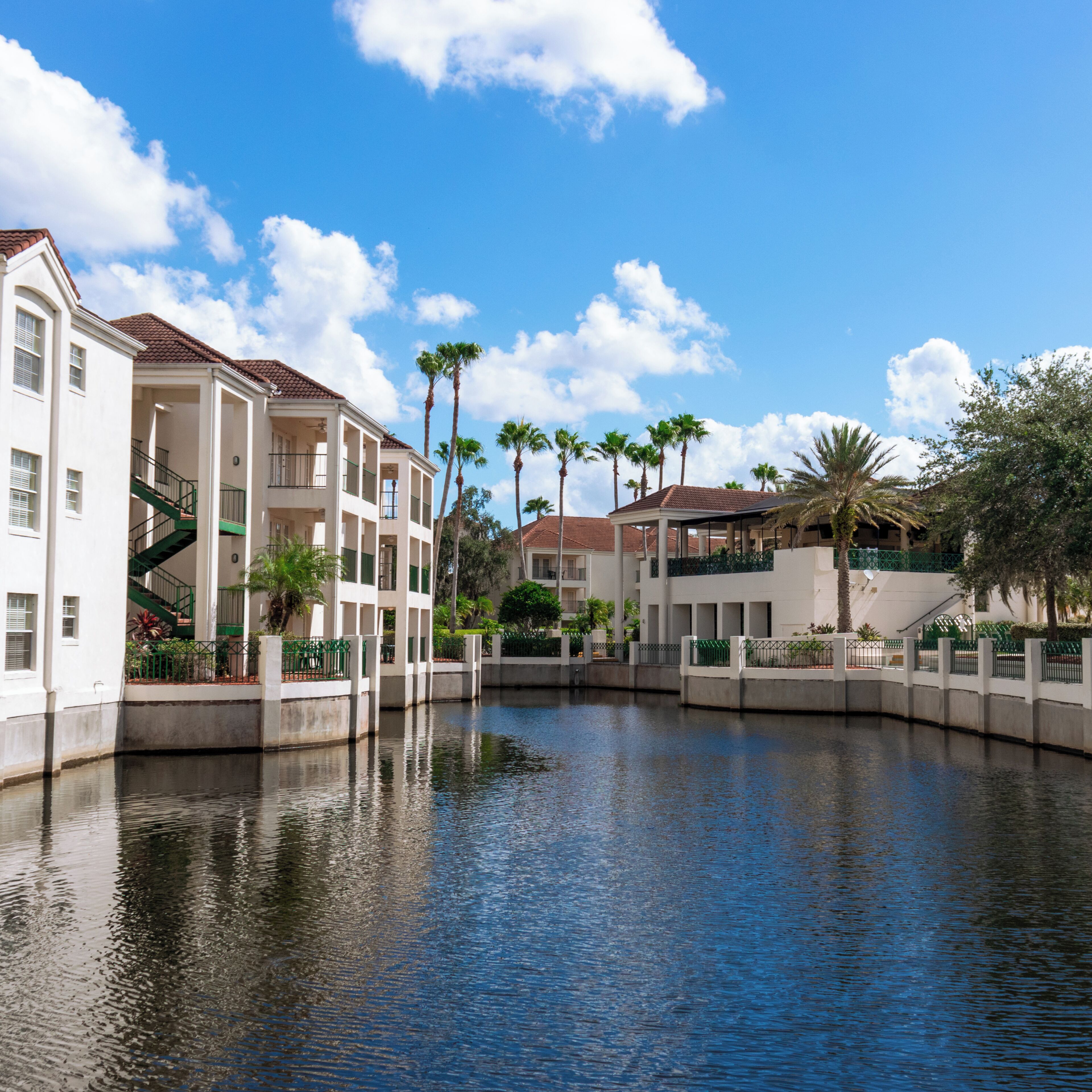 A canal with buildings on either side, including a multi-story structure with balconies and a covered area.