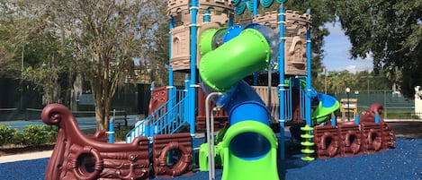 A playground with a castle-like structure, slides, and climbing elements.