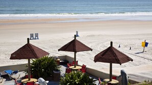 Eine Terrasse direkt am Strand mit Sitzgelegenheiten und Sonnenschirmen mit Blick auf den Ozean.