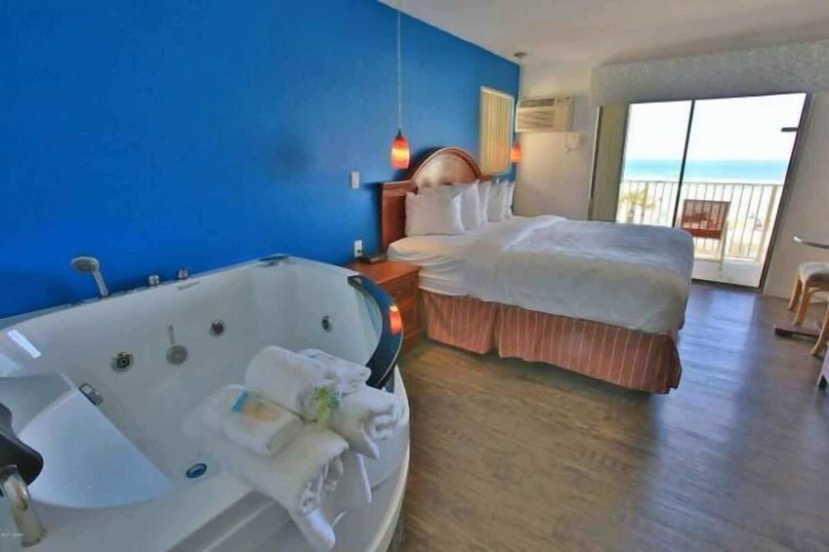 Quarto de hotel com uma cama grande, uma banheira e vista para o oceano.
