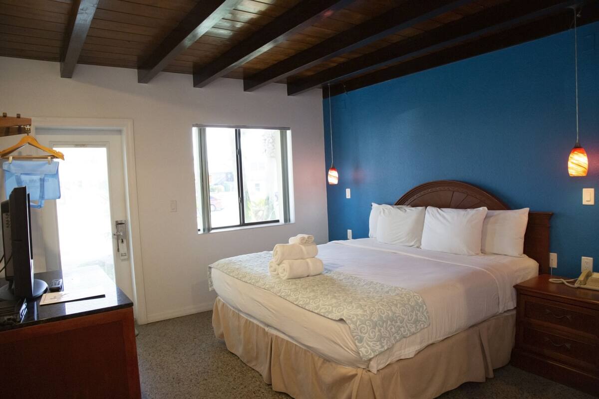 Quarto com cama, penteadeira, televisão e janela.