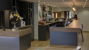 Un espace bar moderne avec un comptoir en bois, un globe décoratif et une variété de bouteilles et de verres.