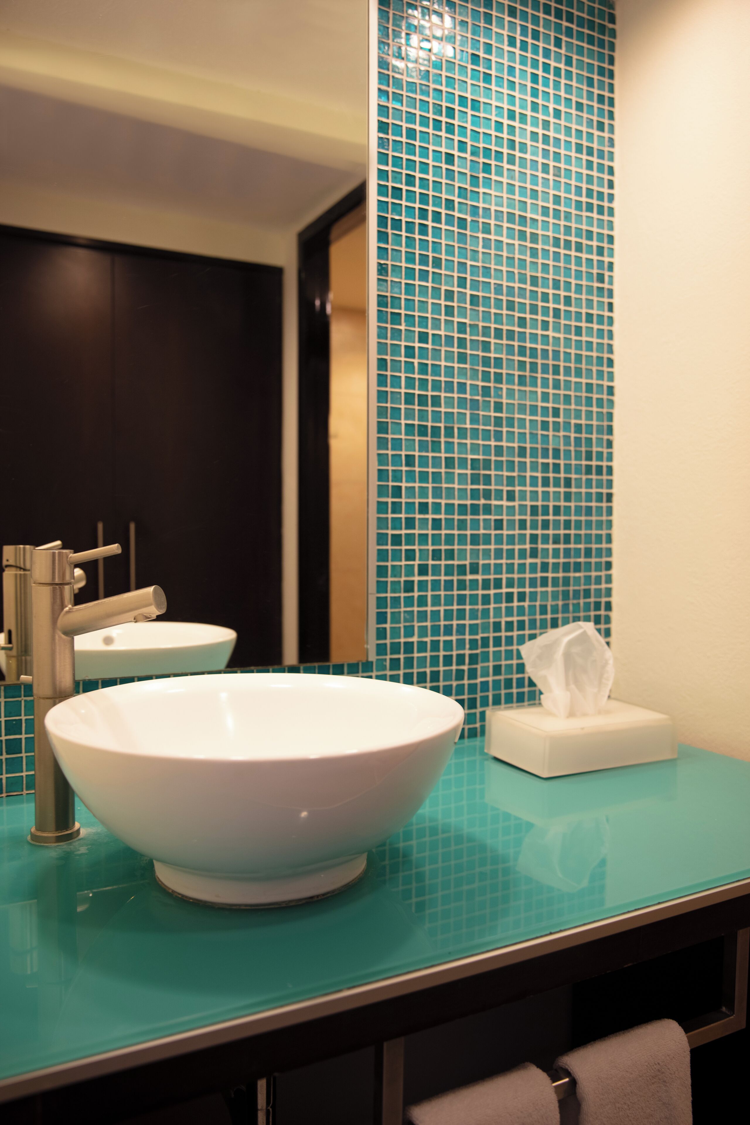 Une salle de bain avec un grand lavabo blanc, un miroir et un mur recouvert de carreaux bleus.