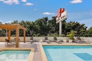 Zona de piscina con sillas de descanso, una pérgola y un letrero que dice 'RESTA INN'.