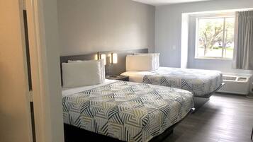 Habitación de hotel con dos camas, una ventana con cortinas y un calentador en la pared.