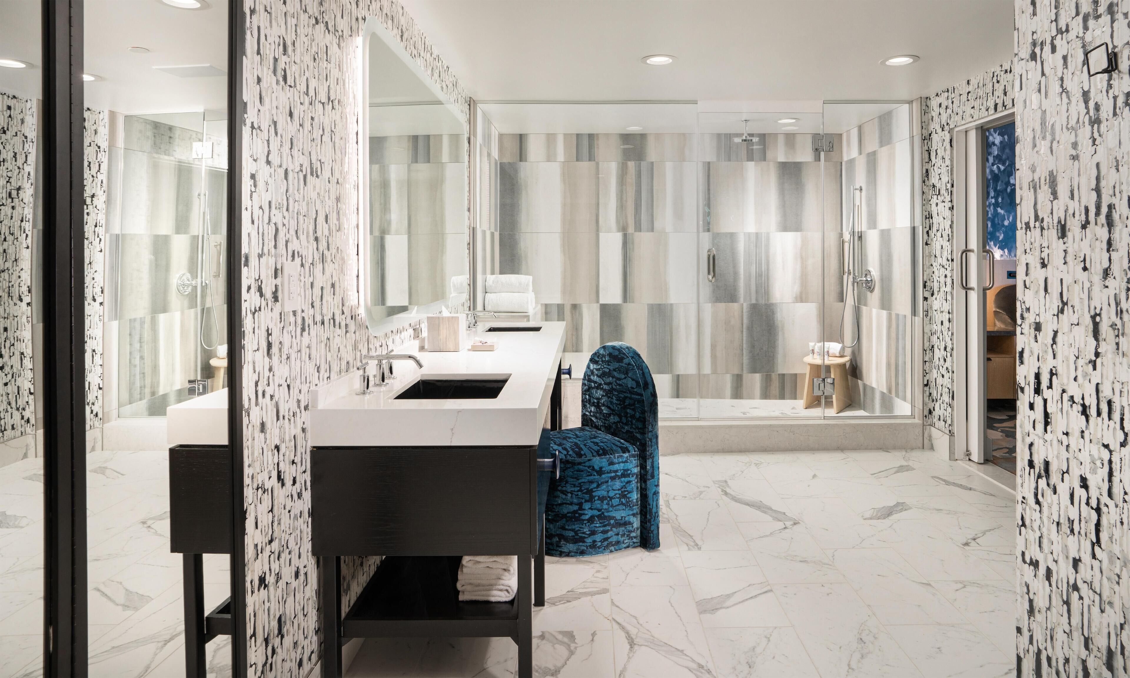 A modern bathroom with a large mirror, a sink, and a shower area.