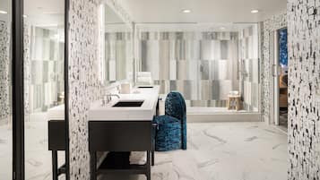 A modern bathroom with a large mirror, a sink, and a shower area.