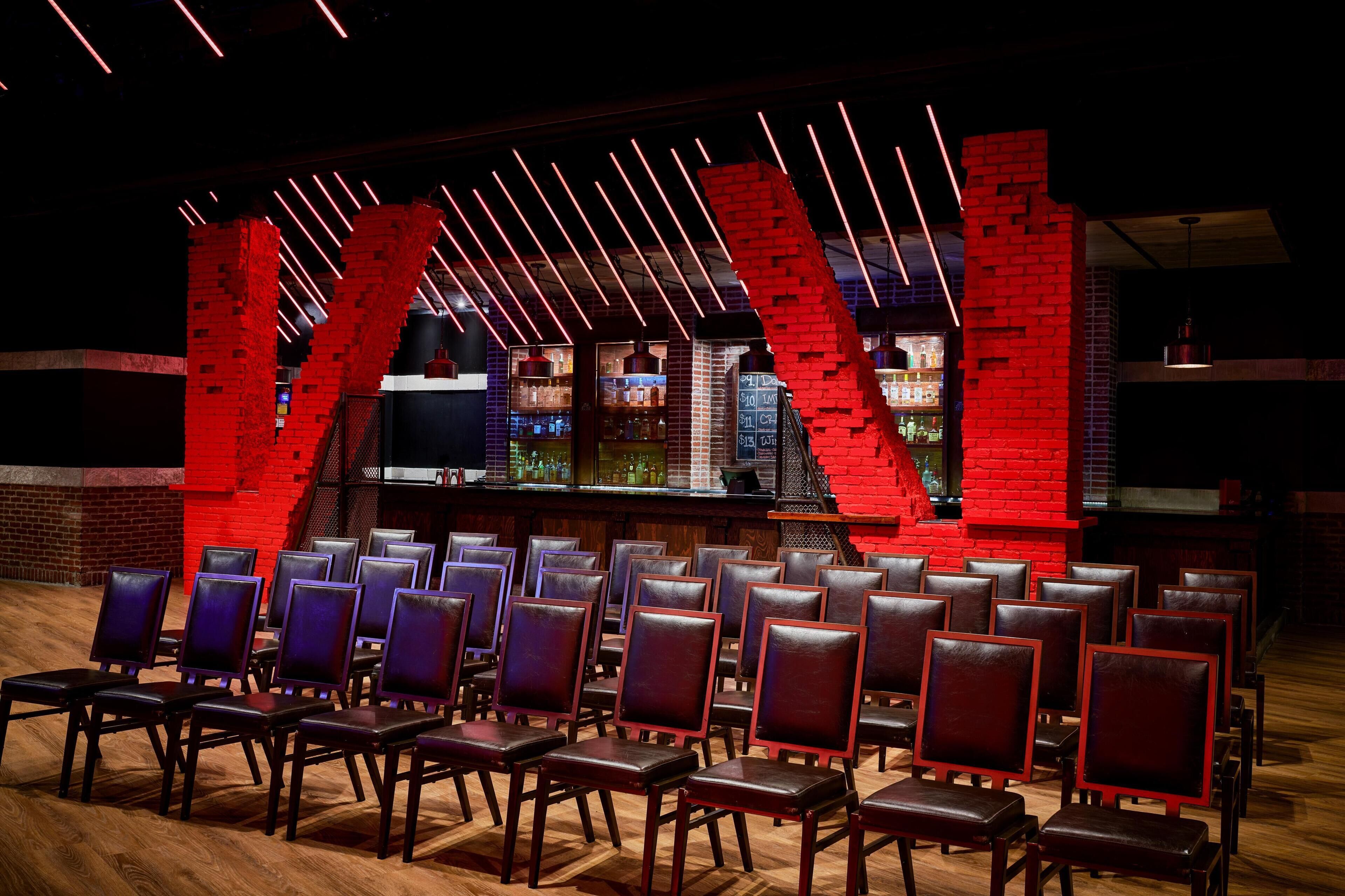 Un espace bar avec des murs en briques rouges, un comptoir où figure le menu et des rangées de chaises.
