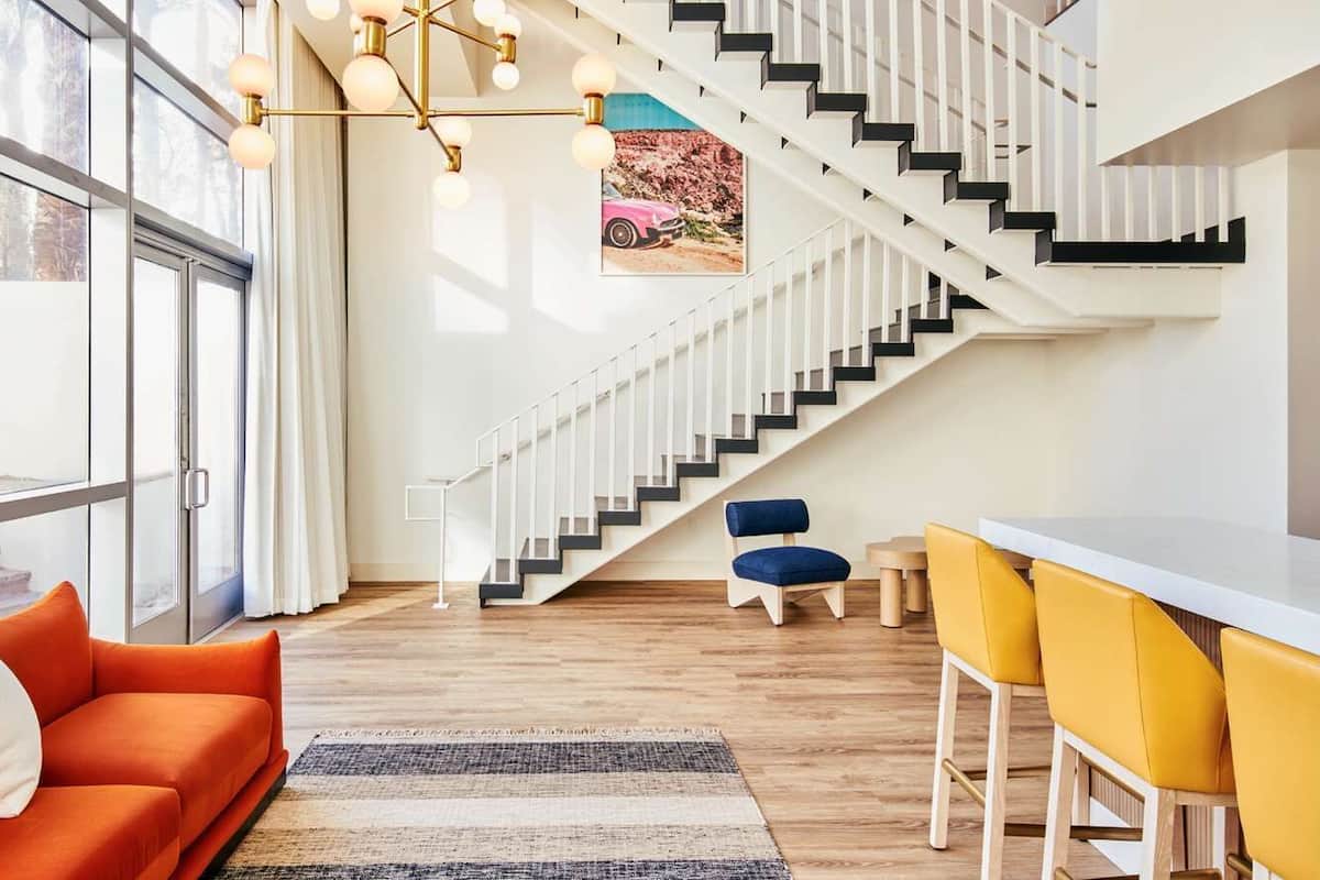 A modern living room with a staircase, a sofa, a coffee table, and a bar area.