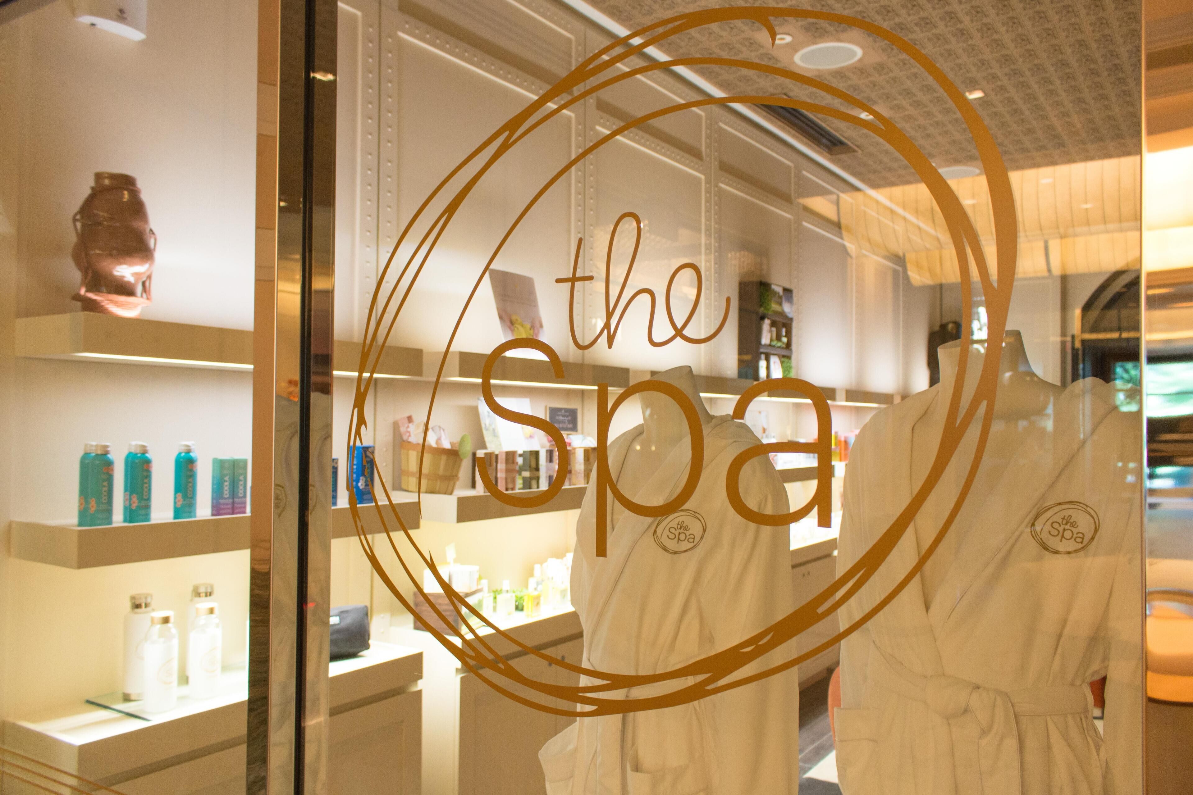 Ein Spa-Bereich mit Glasfront, Regalen für Pflegeprodukte und zwei weißen Bademänteln.