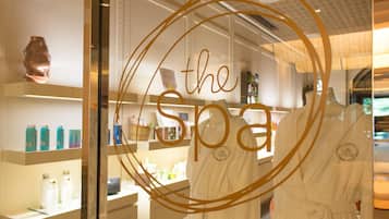 Ein Spa-Bereich mit Glasfront, Regalen für Pflegeprodukte und zwei weißen Bademänteln.