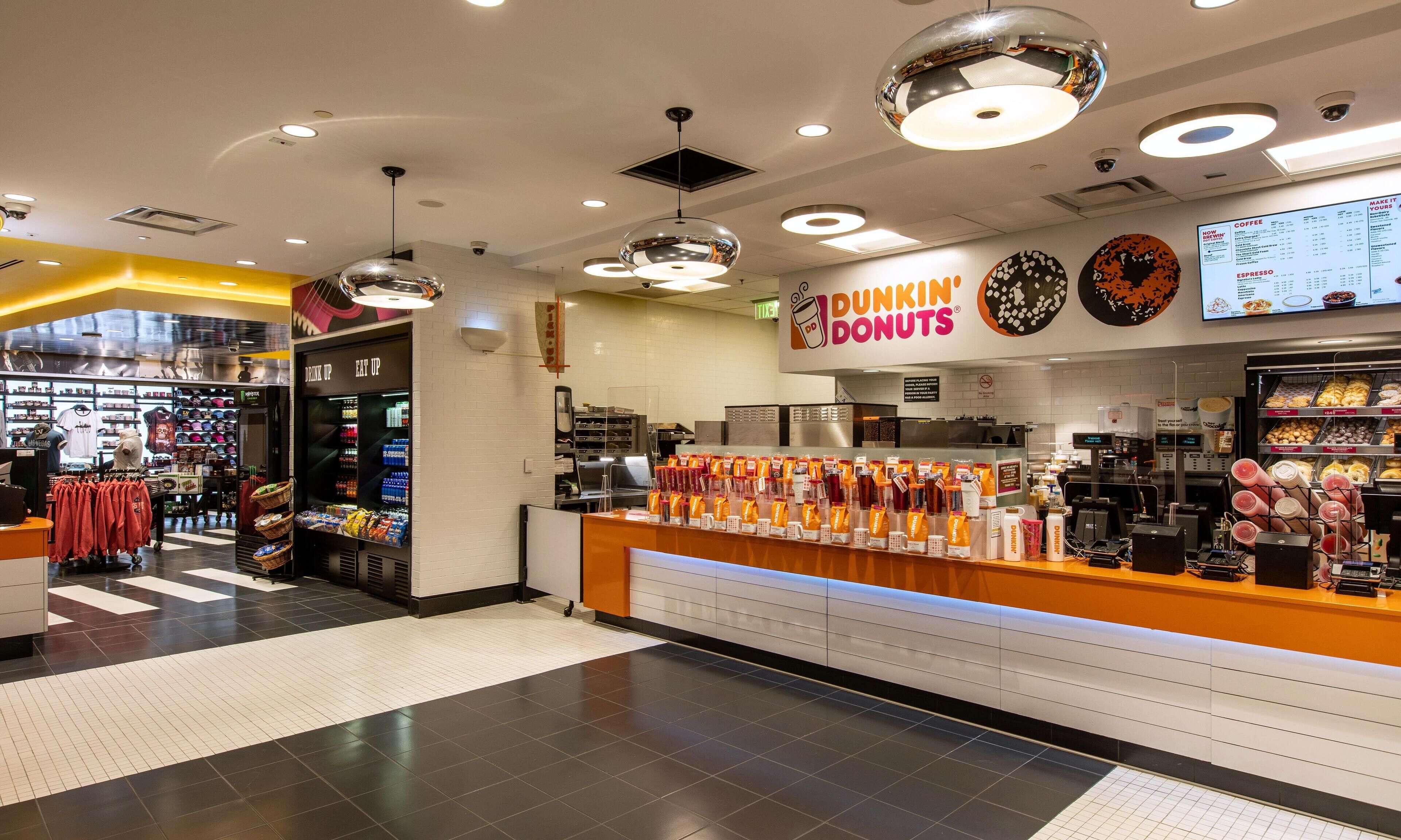 Interior de una tienda Dunkin' Donuts, con mostrador, menú y varios dispensadores de bebidas.